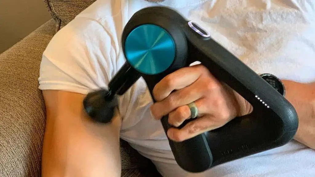 Theragun massager kneads the biceps