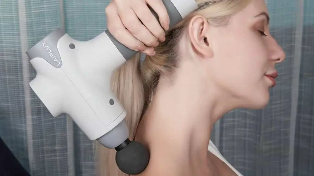 a woman massages the cervical collar area with a white massager