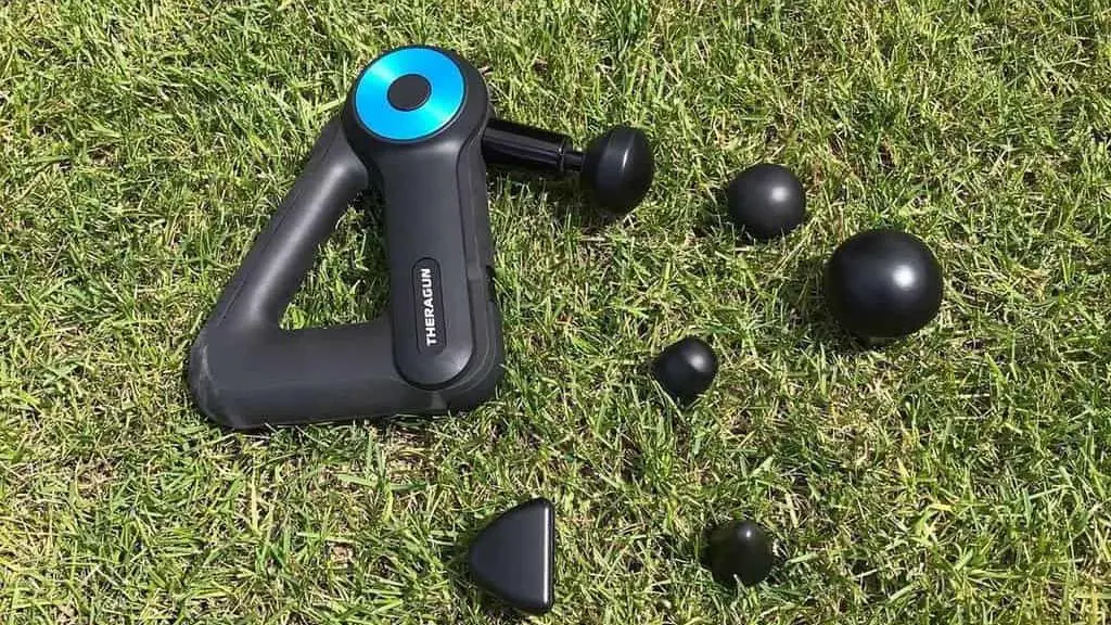 Theragun Massager and its attachments lie on the grass