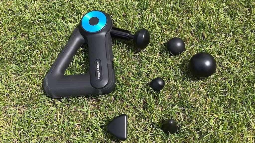 Theragun Massager and its attachments lie on the grass