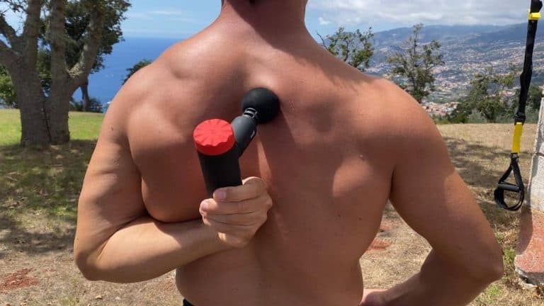 athlete kneads back muscles with a massage gun