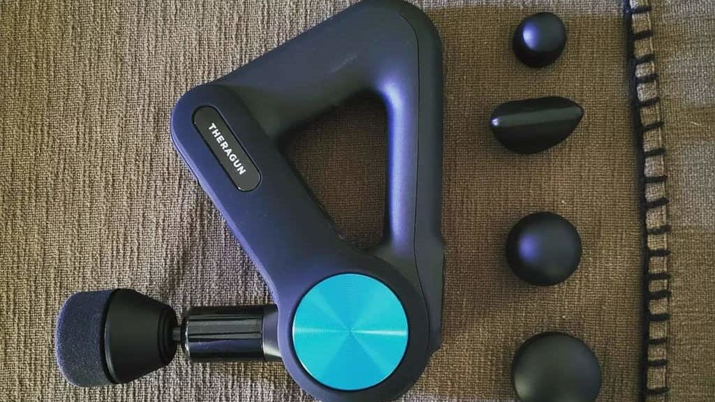 Theragun massager and its attachments are on the couch