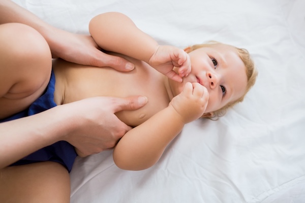 toddler-tummy-and-chest-massage Hands making gentle clockwise circles on a toddler's tummy during a massage