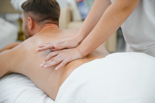 Handsome middle-aged man enjoying relaxing neck and back massage with oils.