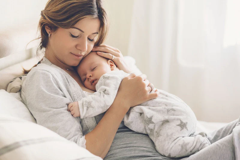 woman cuddling with her baby, looking content and feeling engorged breasts relief