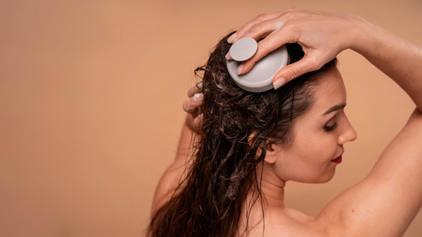 Using a Silicone Scalp Scrubber During Shampoo Scalp Massage Woman using a silicone scalp scrubber to massage and cleanse her scalp while shampooing her hair.