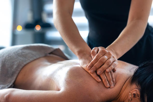 Benefits of Therapeutic Massage Therapy Relaxed woman enjoying therapeutic body massage to reduce stress and muscle tension