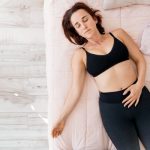 Woman relaxing comfortably in bed representing labia massage, self-care, and female wellness.