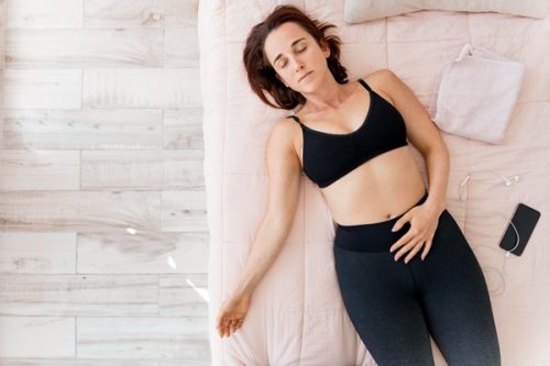 Woman relaxing comfortably in bed representing labia massage, self-care, and female wellness.