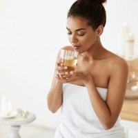African girl drinking water resting in spa salon. Closed eyes.